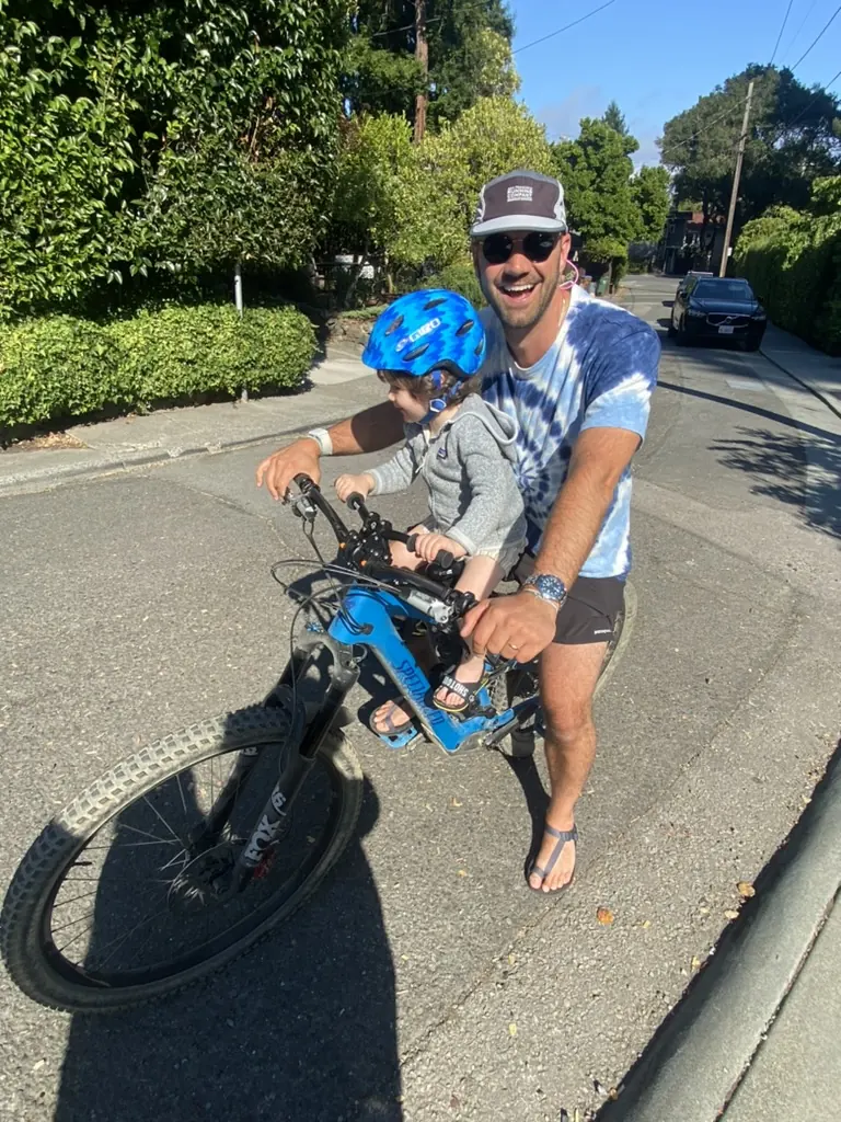 Clifton and a child with a mountain bike on a sunny street